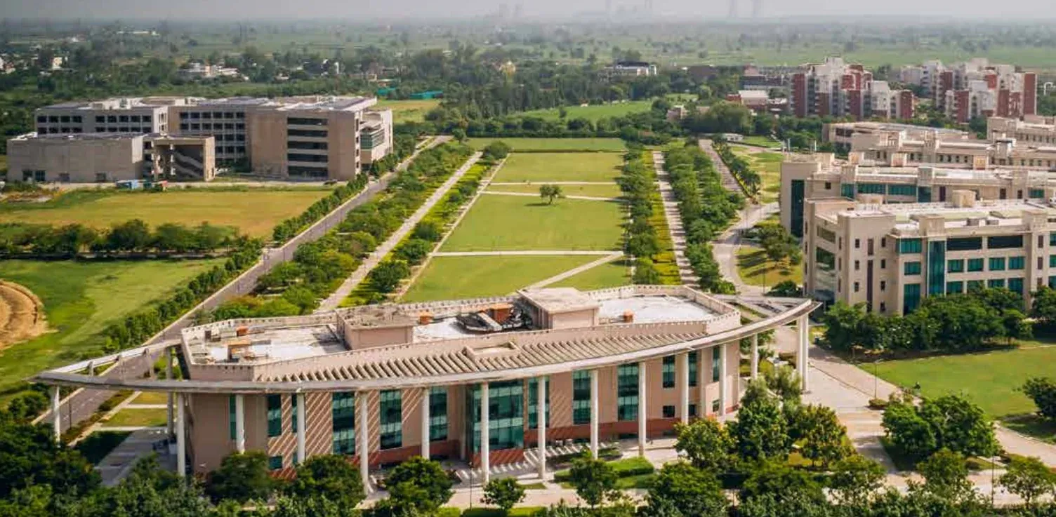 Aerial view of Shiv Nadar University Noida campus showing the main academic block, central lawn, research buildings and student residences across the 286-acre Greater Noida campus